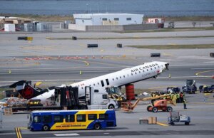 Destroços do avião da Air Canada acidentado sendo retirados da pista do Aeroporto LaGuardia
