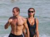 Taron Egerton sem camisa recria a cena icônica de Bond enquanto emerge do mar com a namorada estrela de Baywatch, Brooks Nader, em traje de banho, em meio a sua oferta para o papel de 007