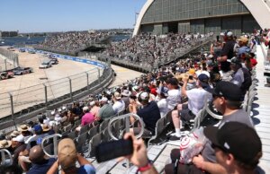 Fan pula cerca durante corrida da NASCAR com bandeira vermelha na Base Naval Coronado de San Diego para encontrar um piloto